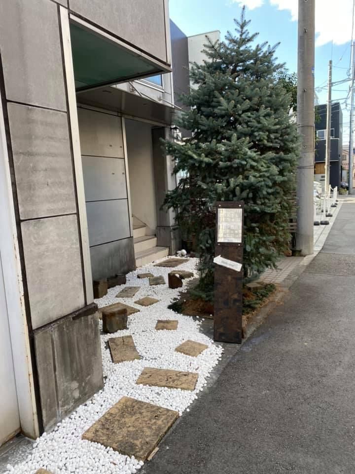 横道側の入口。植え込みのもみの木の奥に階段がある